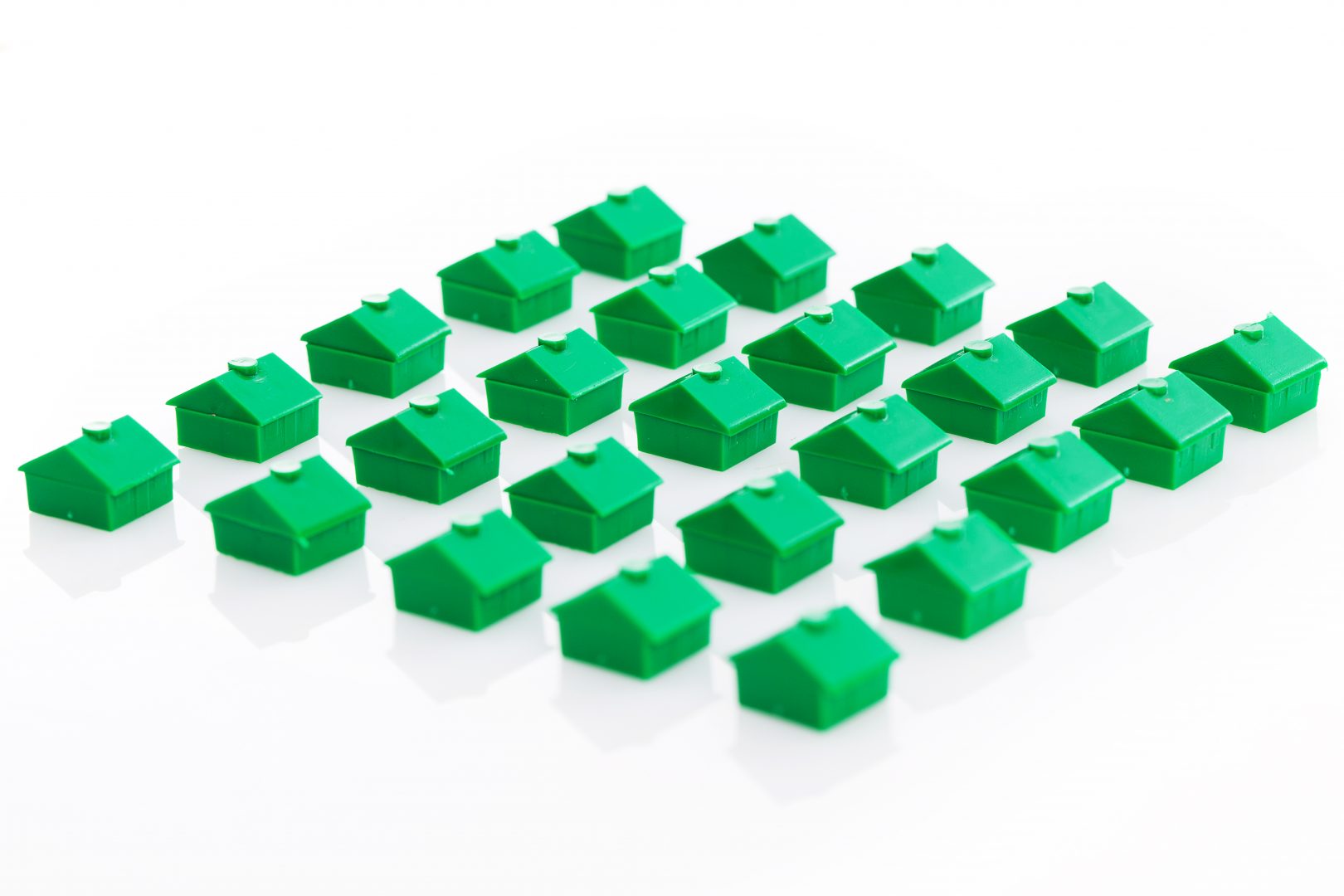 Many green toy houses over a white background